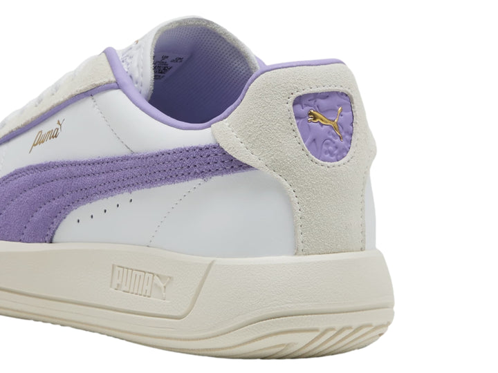 Tenis PUMA blancos con detalle lateral en color lavanda y suela en tono blanco cálido.