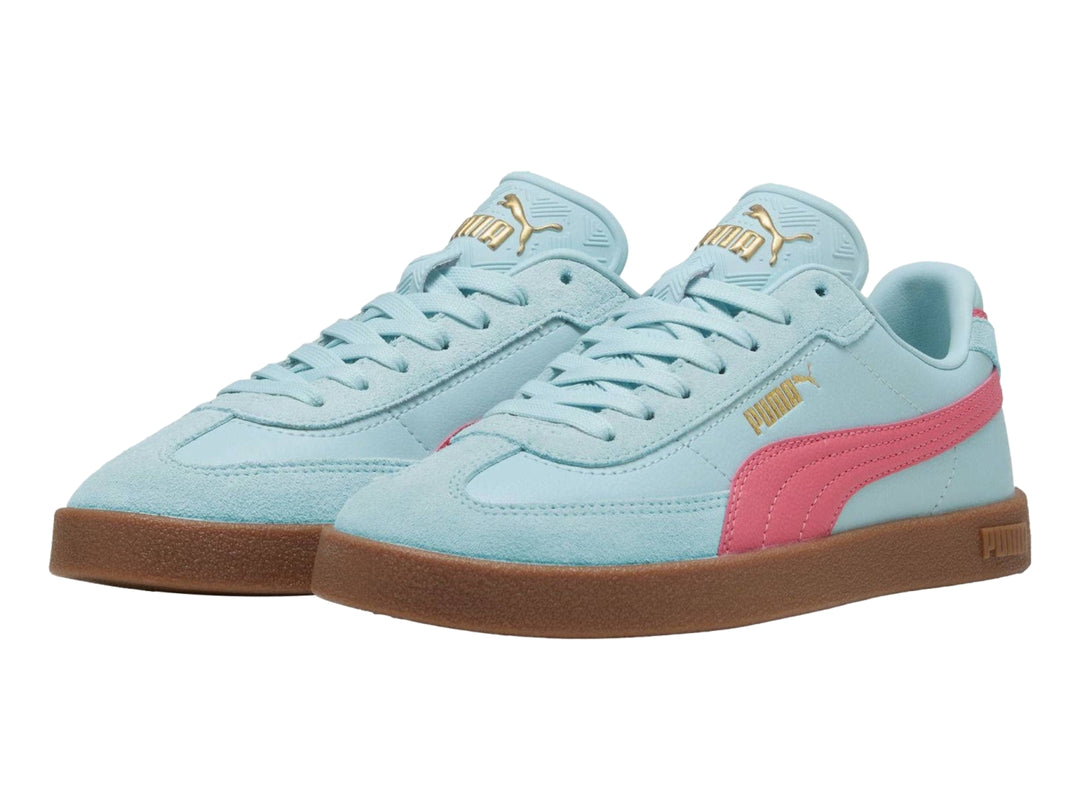 Tenis PUMA color azul claro con franja rosa y suela de goma marrón.
