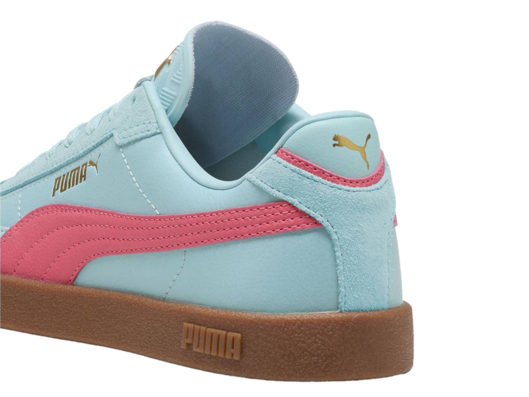Tenis PUMA color azul claro con franja rosa y suela de goma marrón.