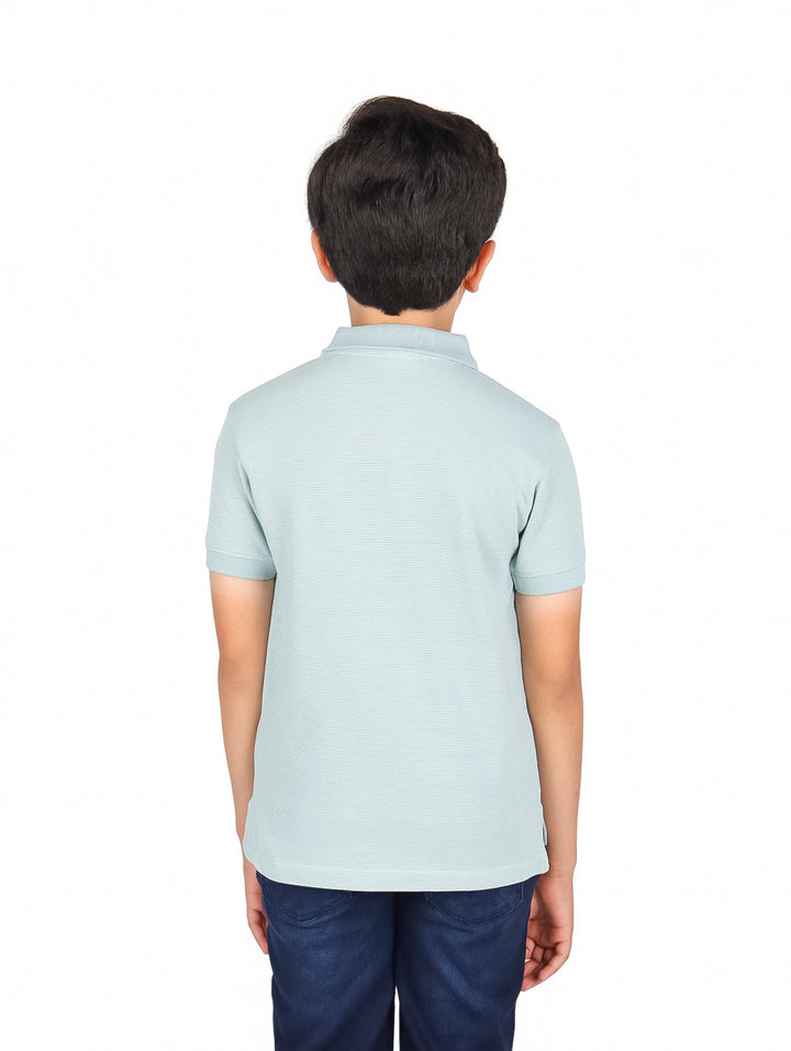 Niño vistiendo una playera polo de color azul claro y pantalones azul marino.