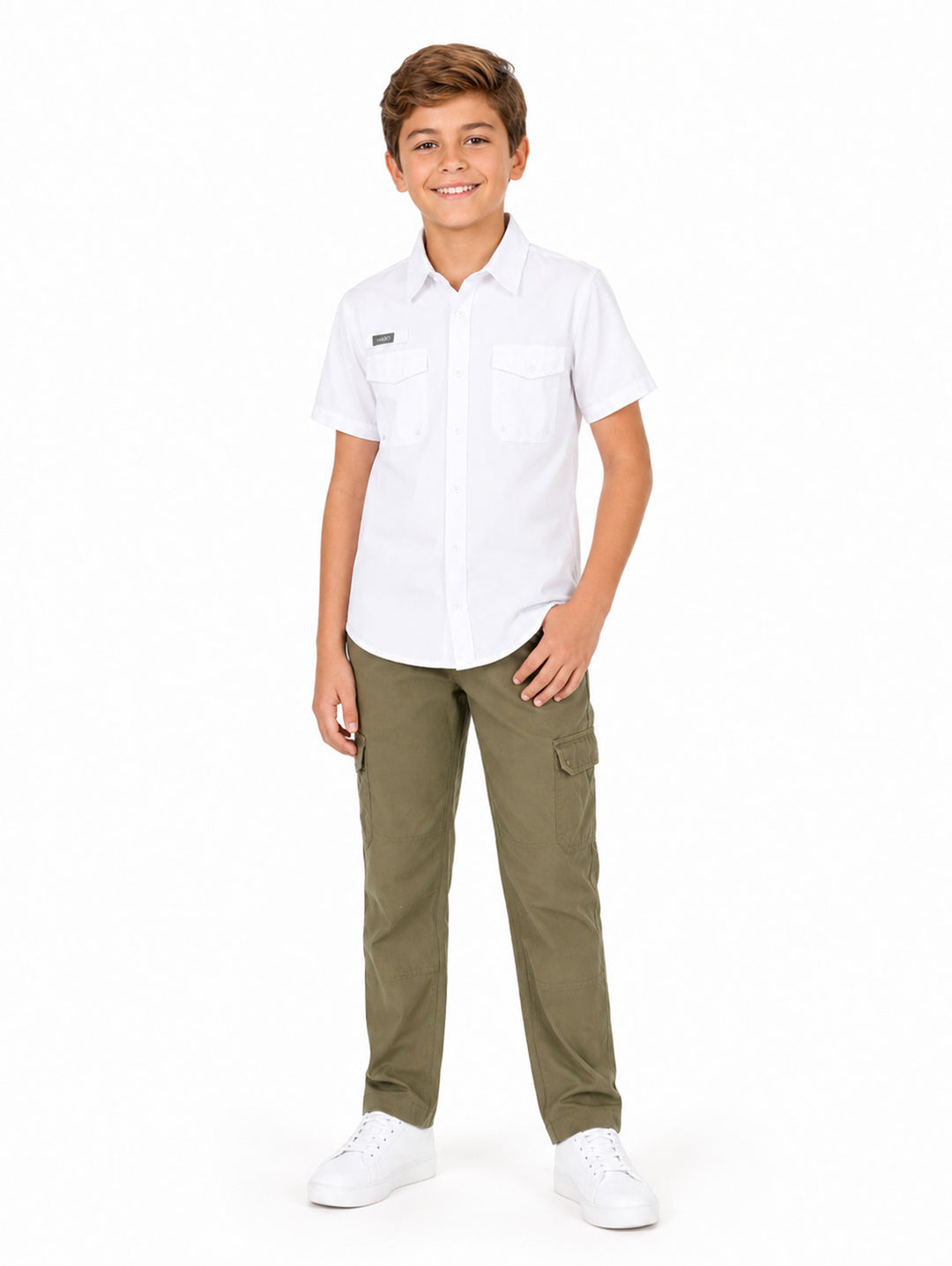 Niño modelando una camisa blanca de manga corta con bolsillos y pantalones cargo color verde oliva.