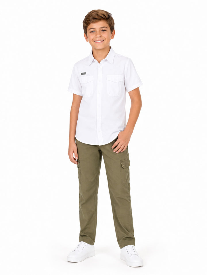 Niño modelando una camisa blanca de manga corta con bolsillos y pantalones cargo color verde oliva.