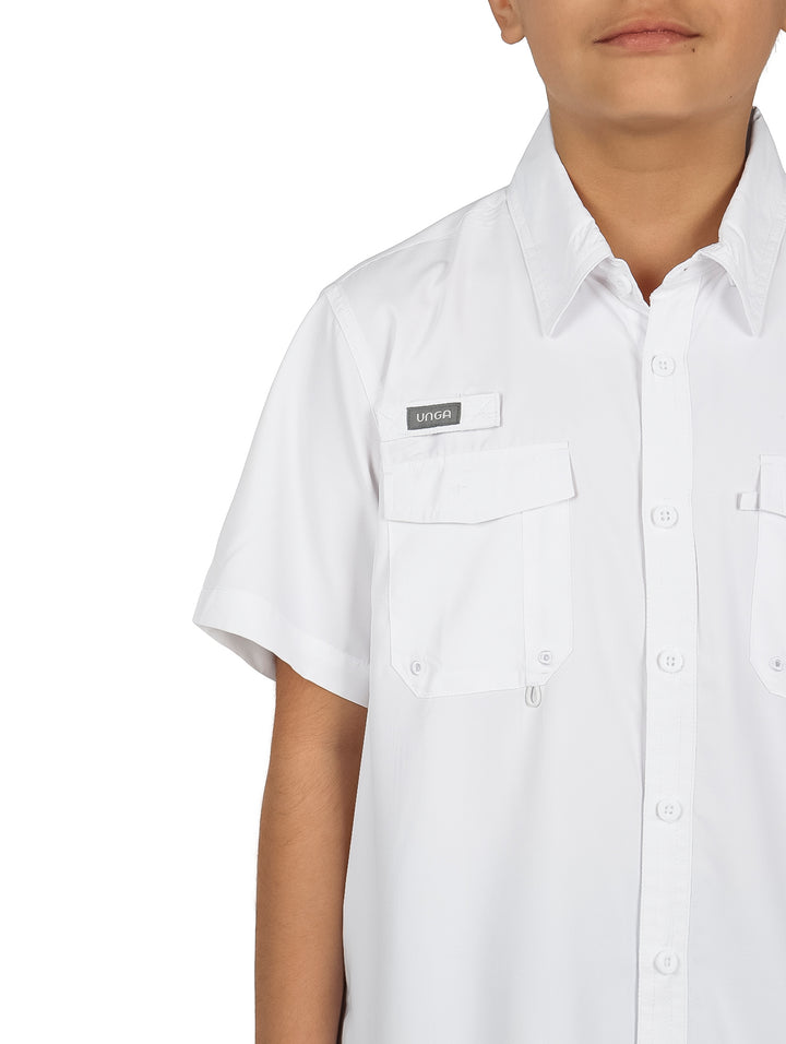 Niño modelando una camisa blanca de manga corta con bolsillos y pantalones cargo color verde oliva.