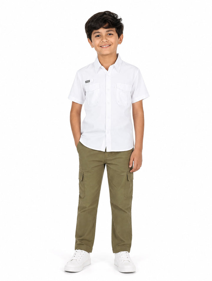 Niño vistiendo una camisa outdoor de color blanco con manga corta y dos bolsillos frontales.