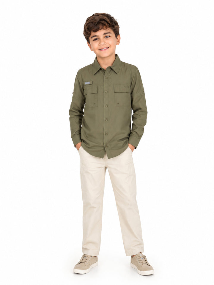 Niño vistiendo camisa de manga larga color verde militar y pantalones beige sobre fondo blanco.