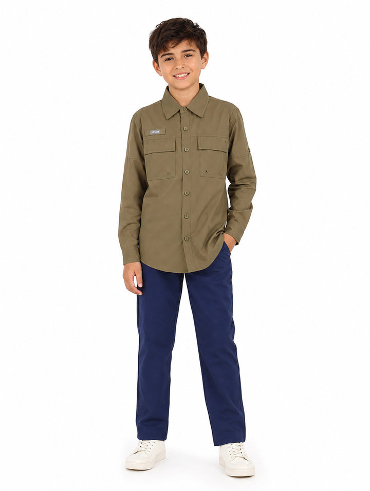 Niño vistiendo una camisa de manga larga color verde militar con dos bolsillos frontales y cuello.
