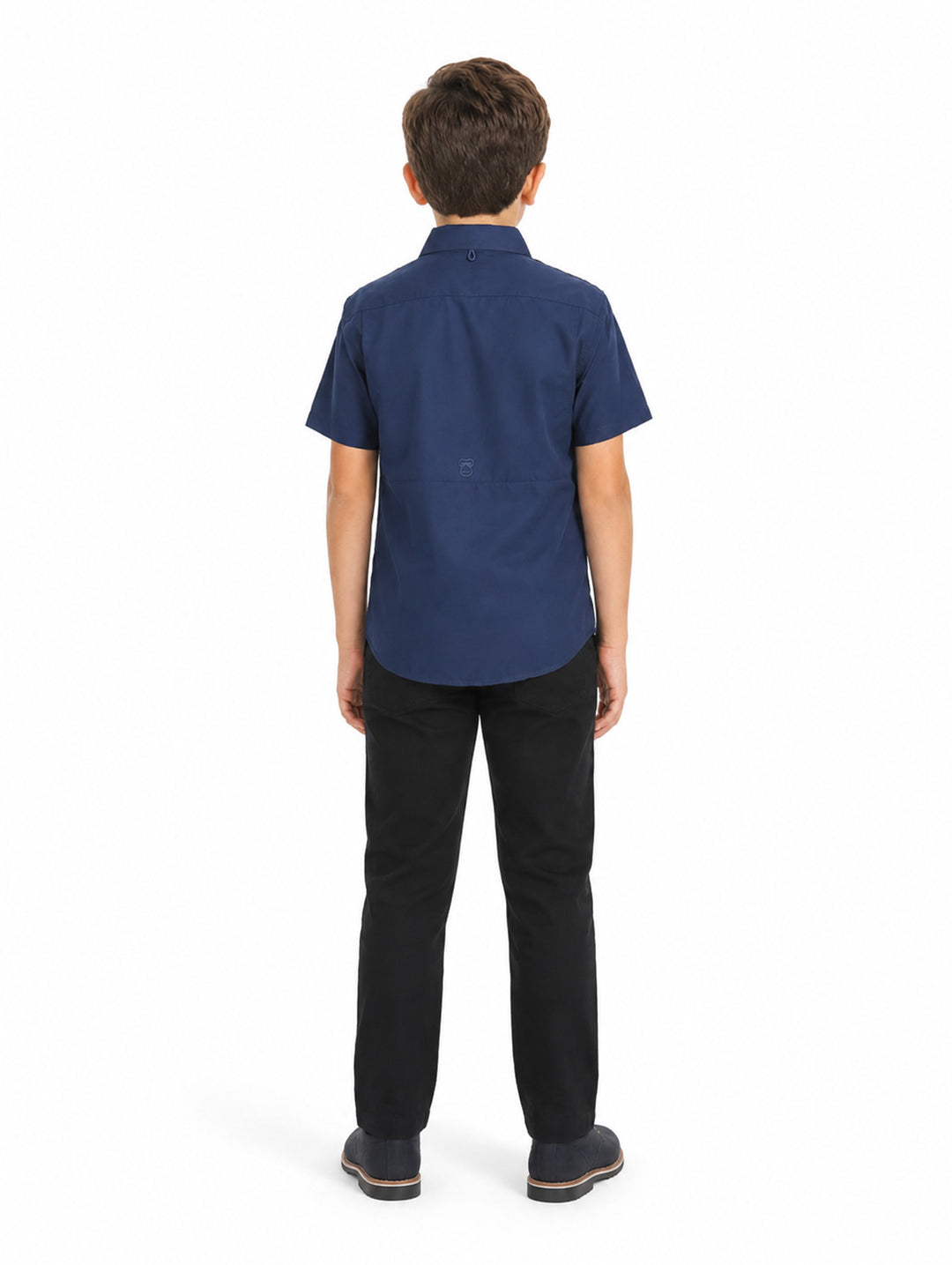 Niño vistiendo una camisa casual color navy de manga corta con bolsillos frontales y pantalones negros.