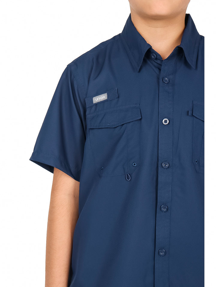 Ni�o vistiendo una camisa casual color navy de manga corta con bolsillos frontales y pantalones negros.