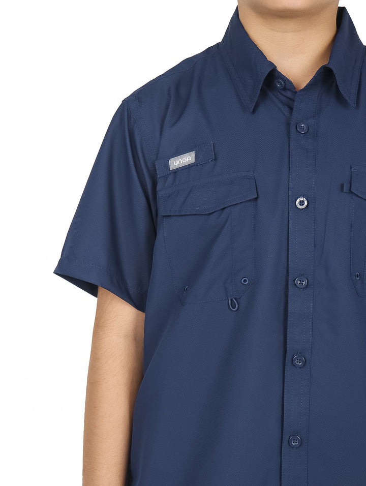 Niño vistiendo una camisa outdoor de manga corta en color azul marino con bolsillos frontales y cuello.