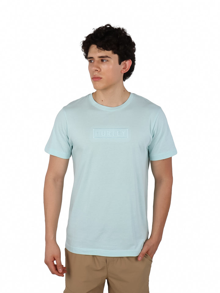 Hombre usando playera Hurley de color teal tinted y pantalones beige.
