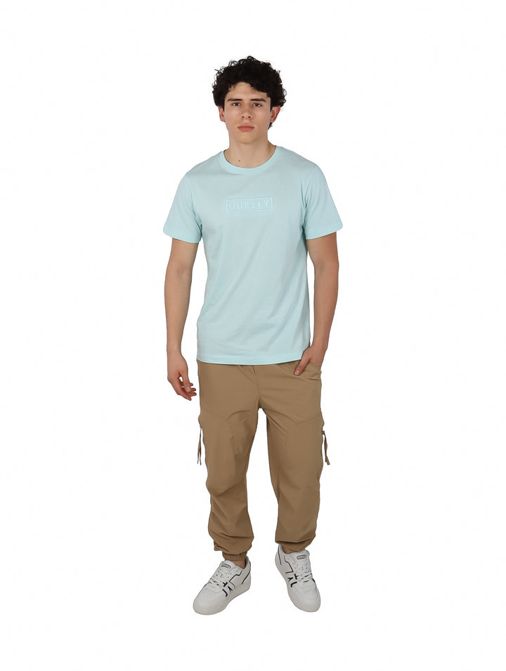 Hombre usando playera Hurley de color teal tinted y pantalones beige.