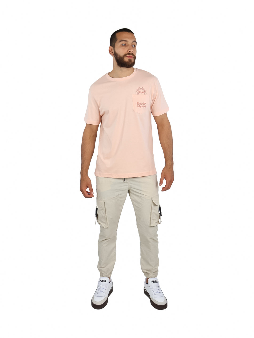 Hombre vistiendo una camiseta de manga corta color rosa claro con un pequeño bolsillo frontal y gráfico.
