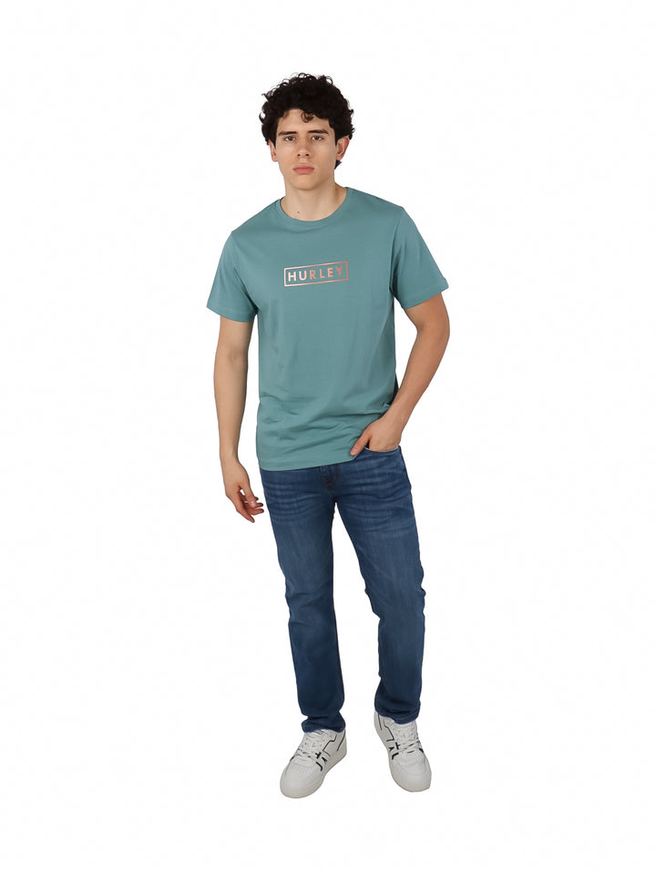 Hombre vistiendo camiseta de manga corta color verde azulado con logo de Hurley en el pecho.