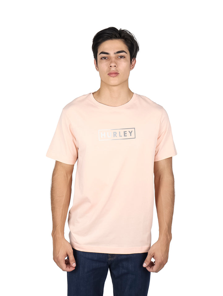 Hombre usando camiseta de manga corta color rosa claro con logo frontal de Hurley.