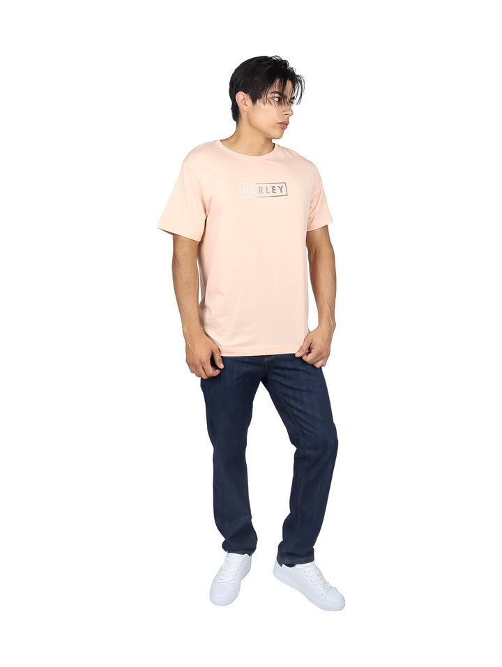 Hombre usando camiseta de manga corta color rosa claro con logo frontal de Hurley.
