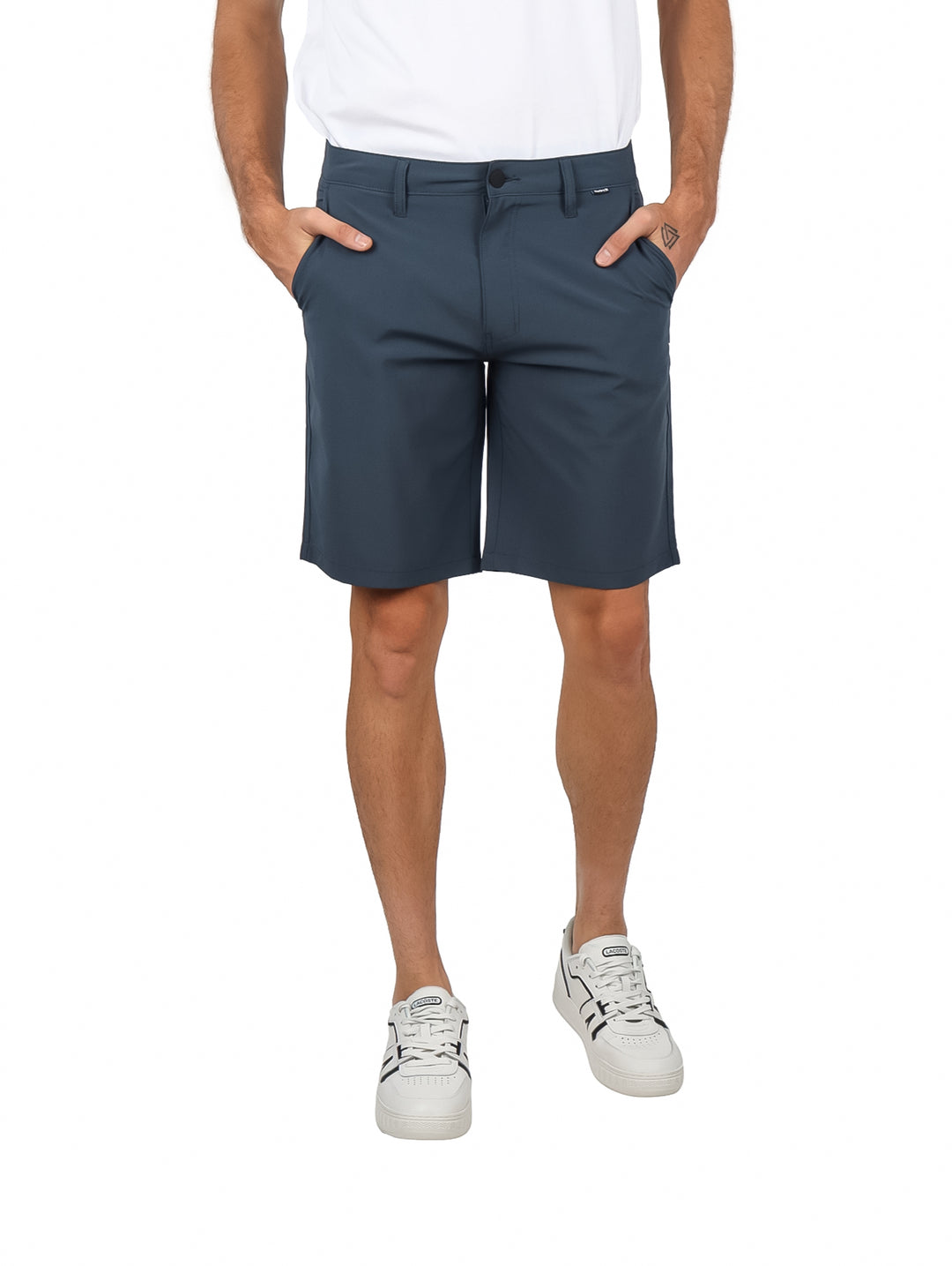 Hombre vistiendo shorts Hurley color gris oscuro Iron Ore con camiseta y tenis blancos.