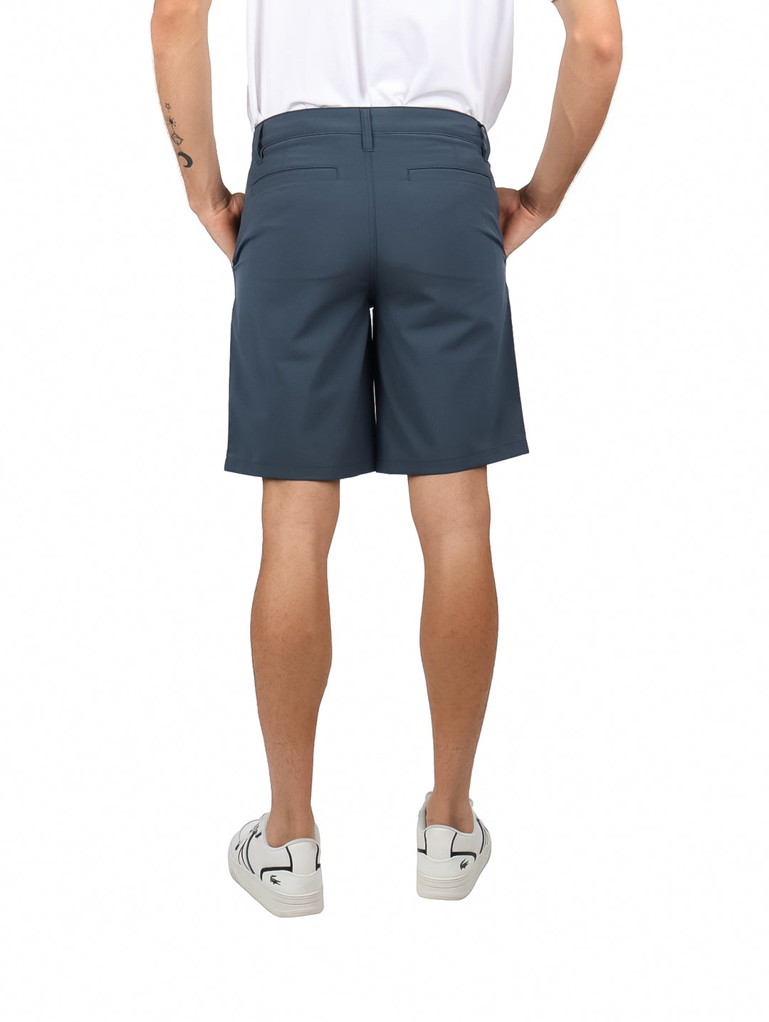 Hombre vistiendo shorts Hurley color gris oscuro Iron Ore con camiseta y tenis blancos.