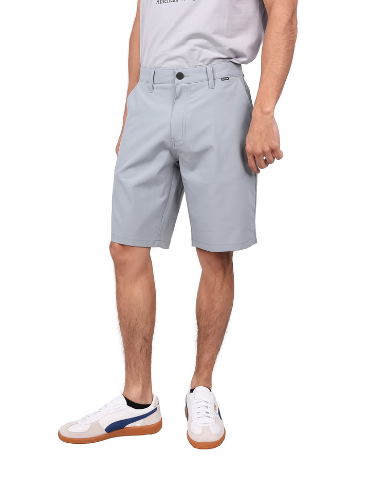 Hombre vistiendo pantalones cortos Hurley color gris gladiador, estilo híbrido y deportivo.