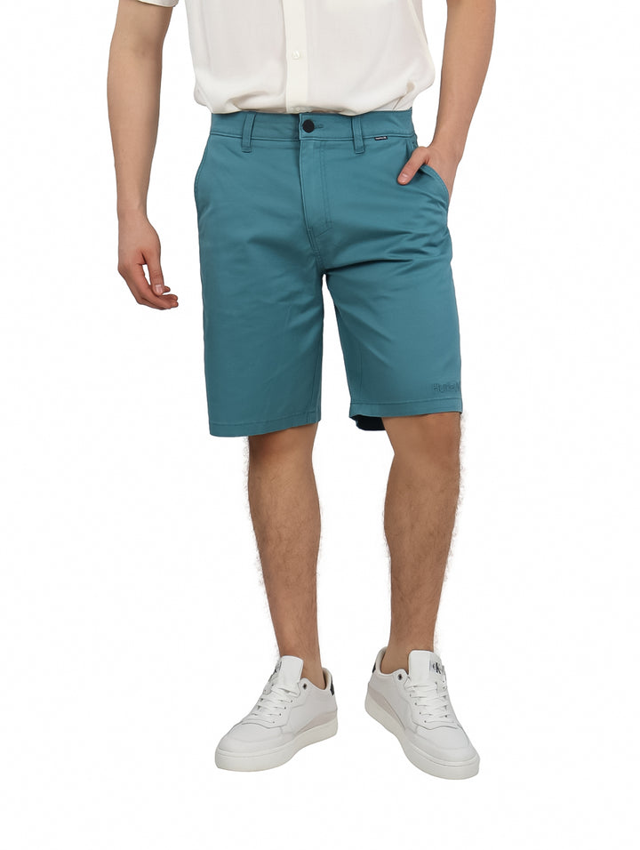 Hombre vistiendo pantalones cortos Hurley color Deep Emerald de corte clásico y textura mate.