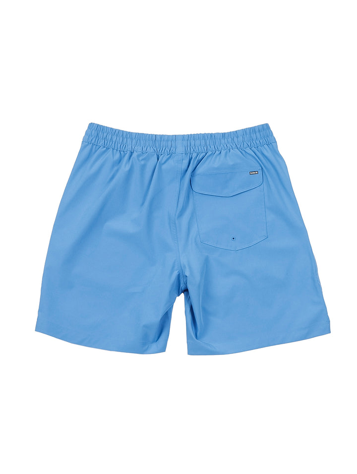 Hombre vistiendo shorts de natación Hurley color azul claro con camiseta blanca y tenis blancos.