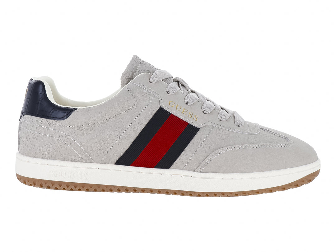 Tenis Guess color natural con franjas azul y rojo en el lateral, suela blanca y detalles en azul marino.