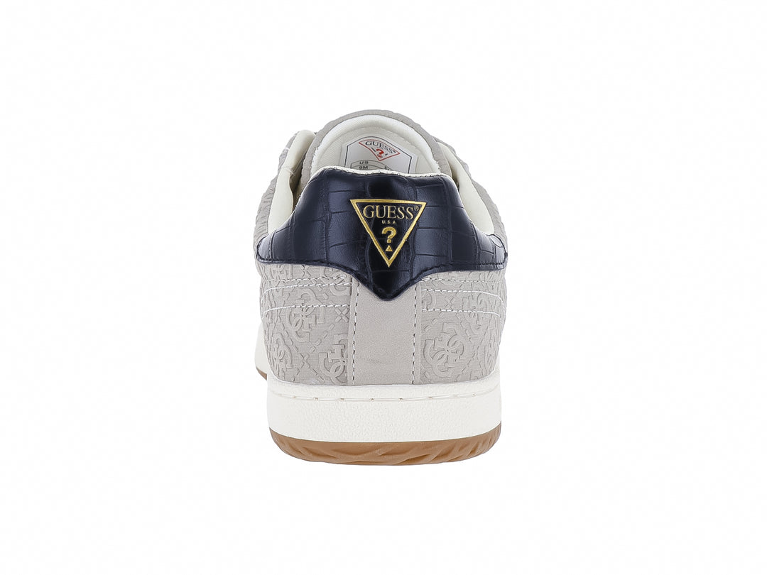 Tenis Guess color natural con franjas azul y rojo en el lateral, suela blanca y detalles en azul marino.