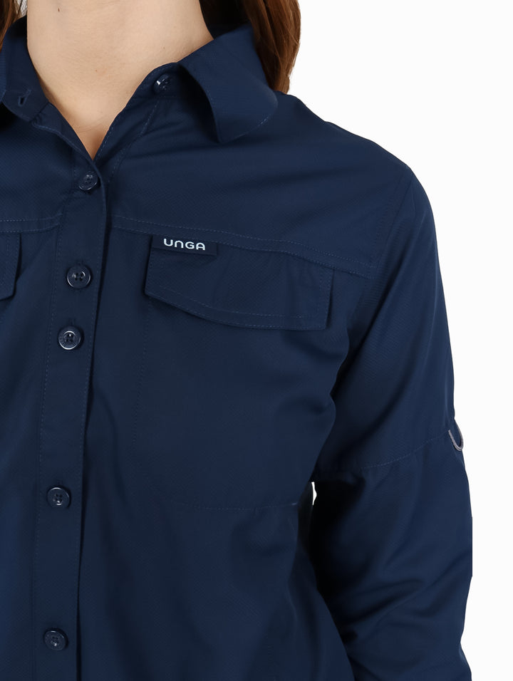 Mujer vistiendo una camisa UNGA de manga larga en color azul navy con bolsillos frontales y estilo outdoor.