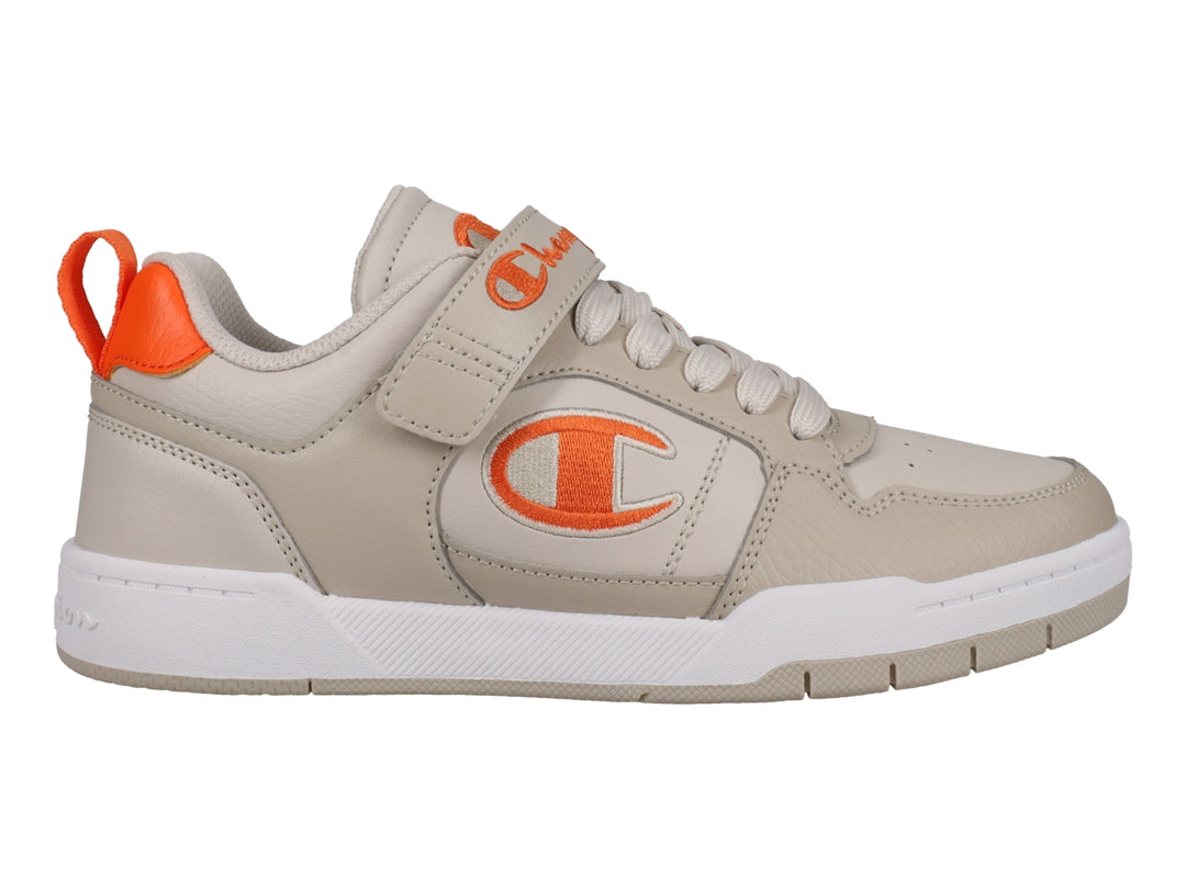 Tenis Champion color beige con detalles en naranja, suela blanca y cierre de agujetas con correa de velcro.
