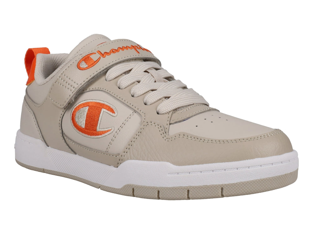 Tenis Champion color beige con detalles en naranja, suela blanca y cierre de agujetas con correa de velcro.