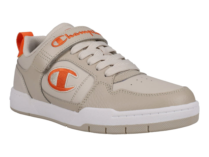 Tenis Champion color beige con detalles en naranja, suela blanca y cierre de agujetas con correa de velcro.