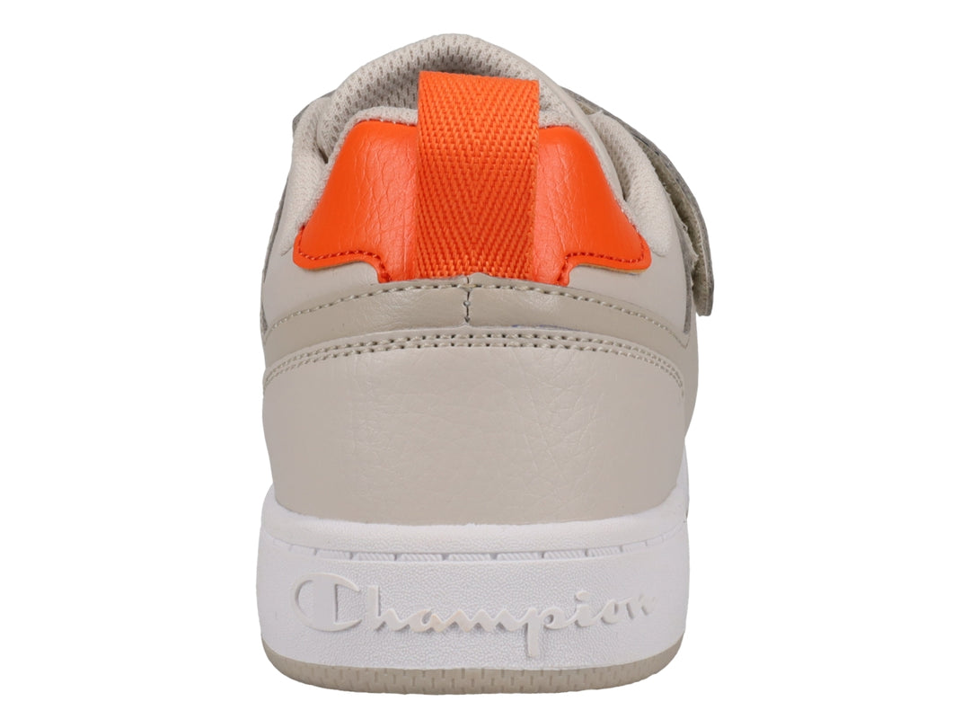 Tenis Champion color beige con detalles en naranja, suela blanca y cierre de agujetas con correa de velcro.
