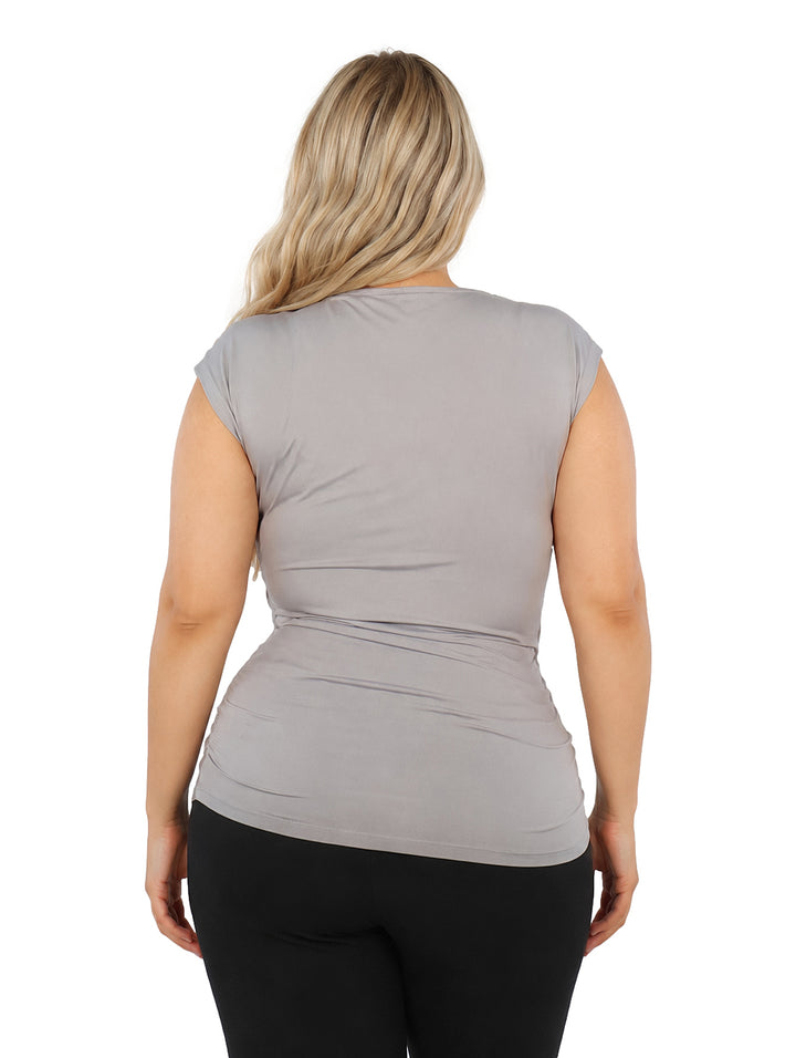 Mujer vistiendo blusa color gris con cuello asimétrico y corte sin mangas.
