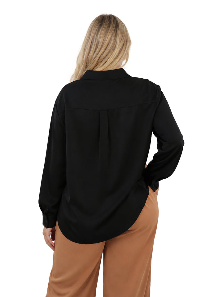 Mujer vistiendo una camisa negra de manga larga con cuello y botones, estilo casual.
