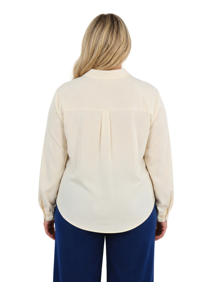 Mujer vistiendo una camisa holgada de color ivory con cuello y mangas largas.