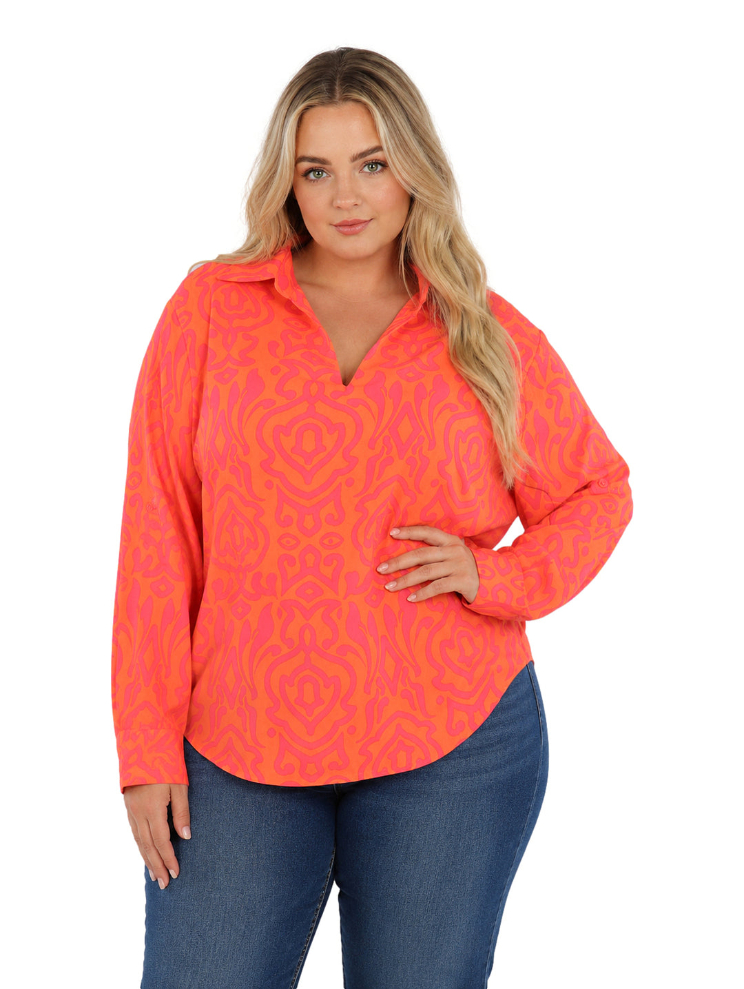 Mujer vistiendo camisa de botones con estampado abstracto en tonos naranja y rosa, de corte amplio y manga larga.