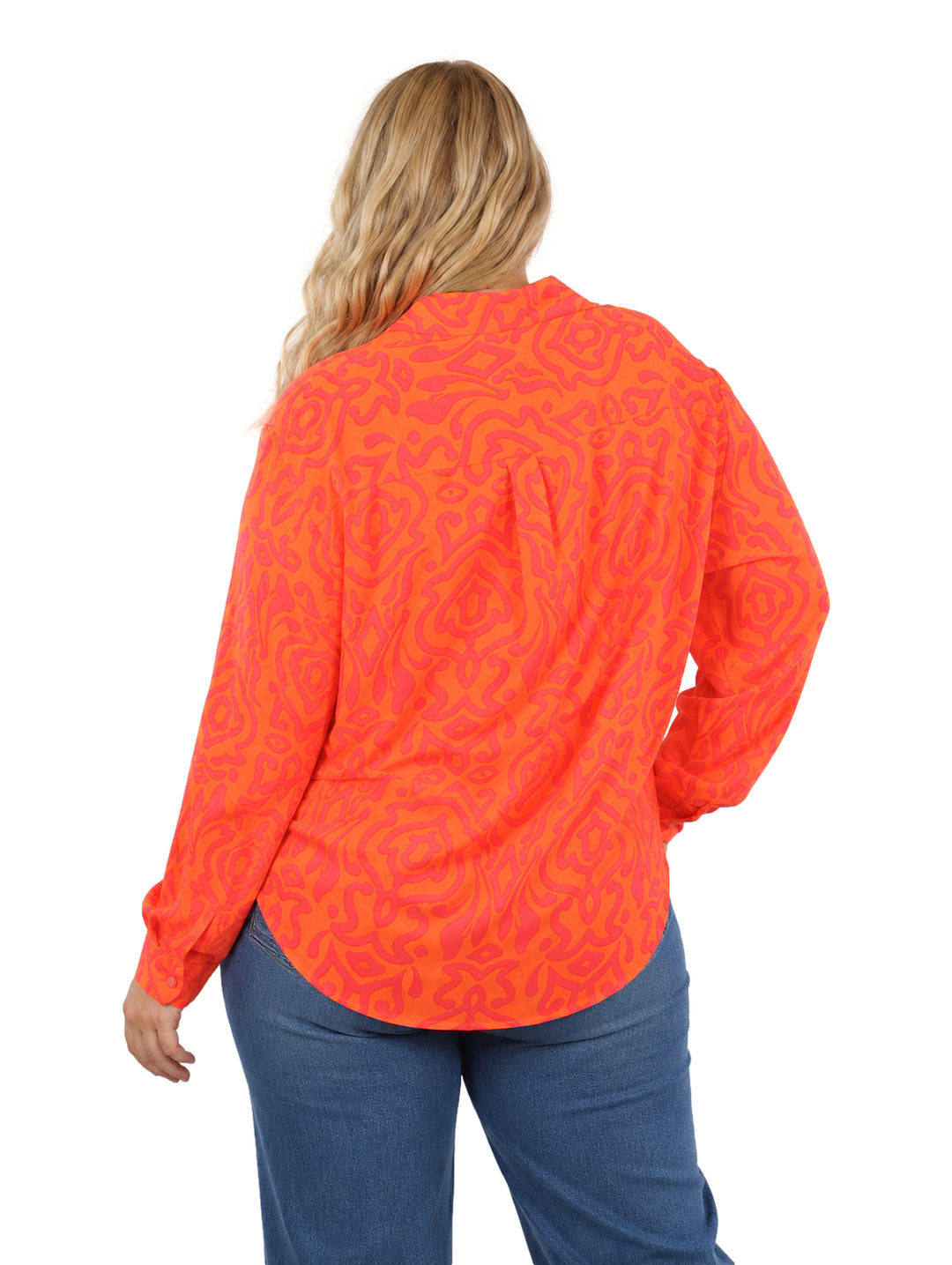 Mujer vistiendo camisa de botones con estampado abstracto en tonos naranja y rosa, de corte amplio y manga larga.