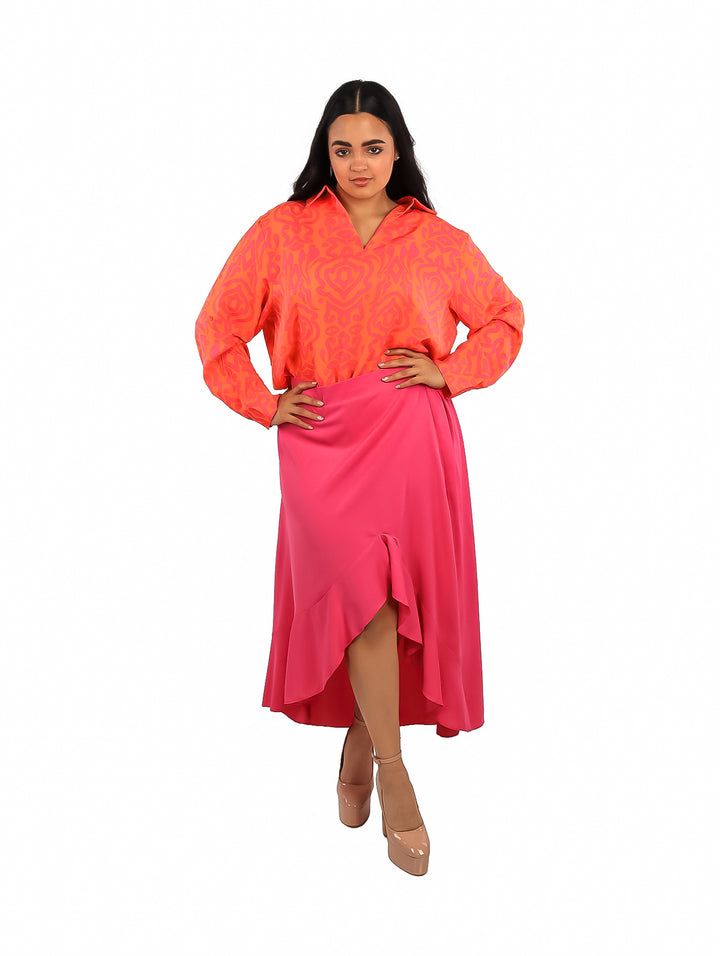 Mujer vistiendo falda satinada color magenta de corte largo con abertura frontal y detalles de volantes.