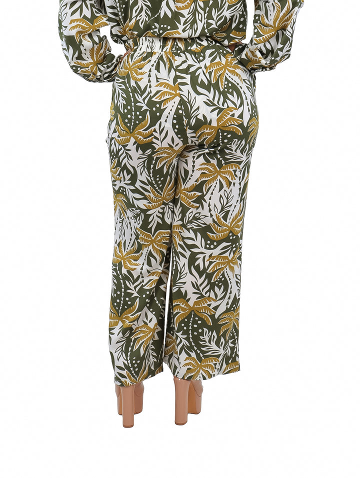 Pantalón ancho con estampado de hojas tropicales en colores verde, blanco y amarillo.