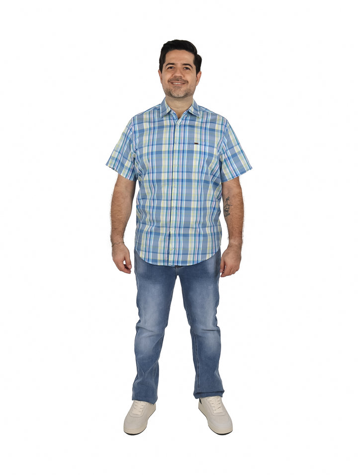 Hombre vistiendo una camisa de manga corta con estampado de cuadros en azul, blanco y amarillo.