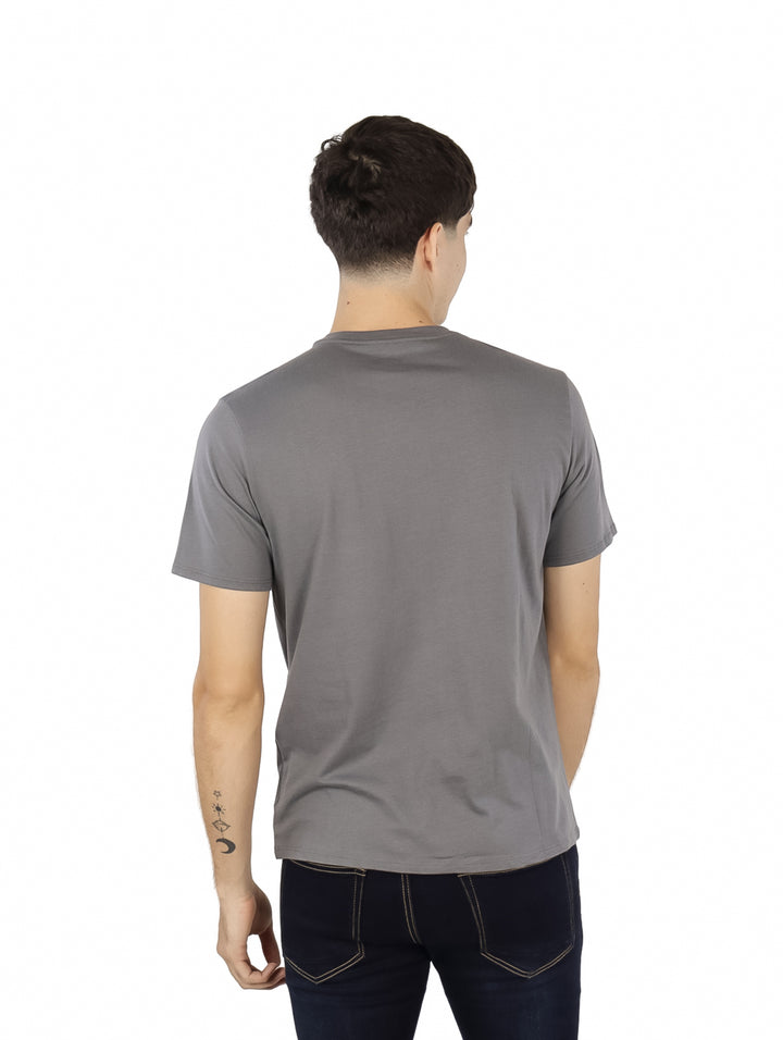 Hombre vistiendo playera gris de manga corta marca Wrangler con estampado de cowboy en el pecho.