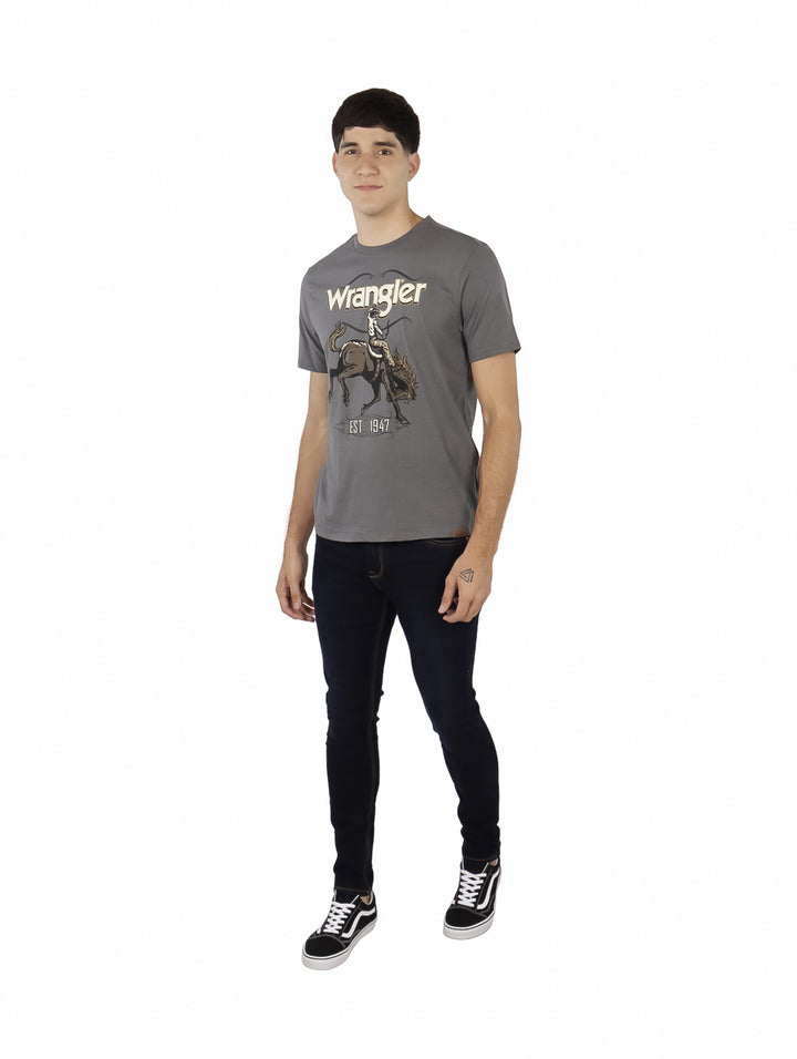 Hombre vistiendo playera gris de manga corta marca Wrangler con estampado de cowboy en el pecho.