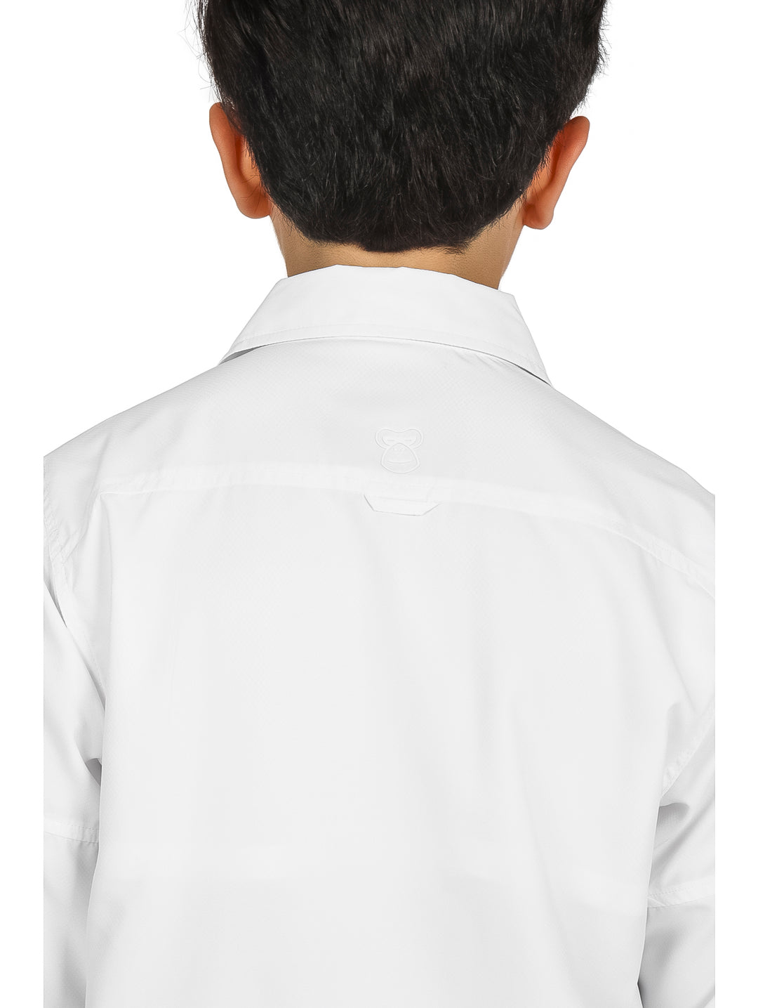 Niño vistiendo una camisa blanca de manga larga y pantalones negros sobre fondo blanco.