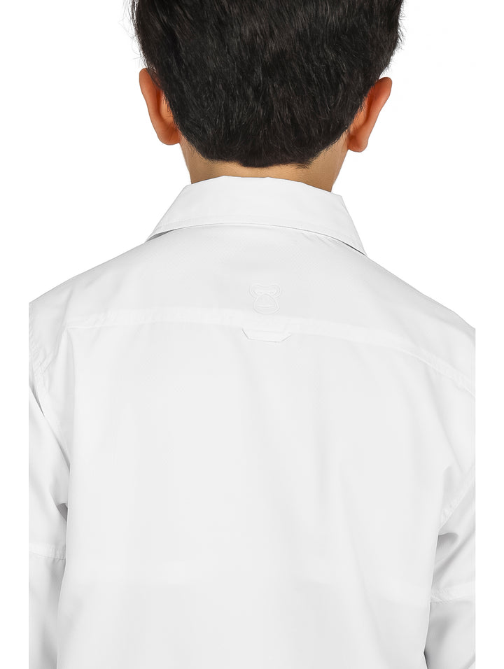Niño vistiendo una camisa blanca de manga larga y pantalones negros sobre fondo blanco.