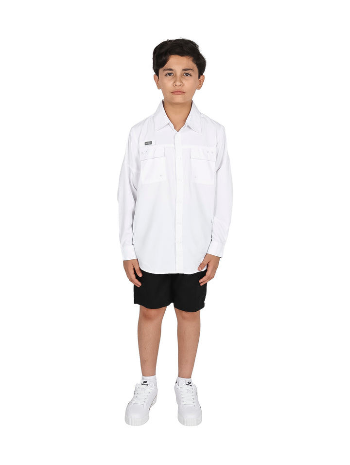 Niño vistiendo una camisa blanca de manga larga y pantalones negros sobre fondo blanco.