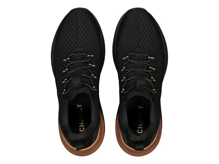 Tenis deportivos color negro con acento dorado en el talón y detalles en las agujetas.