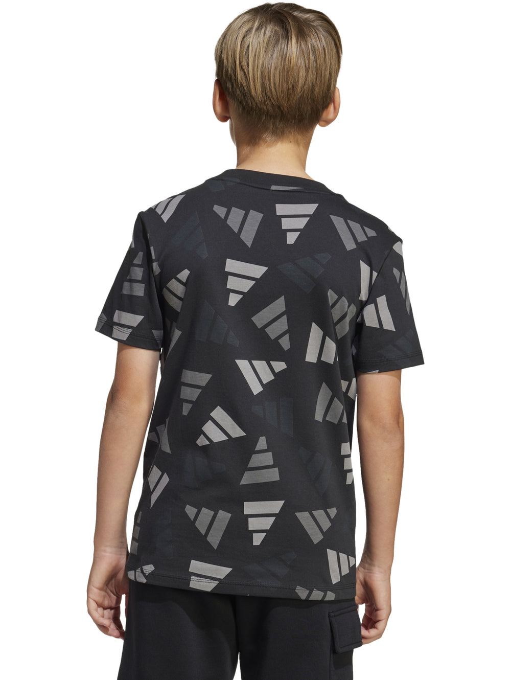 Niño vistiendo playera Adidas negra con estampado geométrico en gris y pantalones negros.