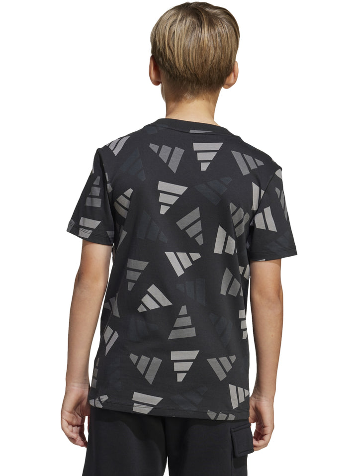 Niño vistiendo playera Adidas negra con estampado geométrico en gris y pantalones negros.