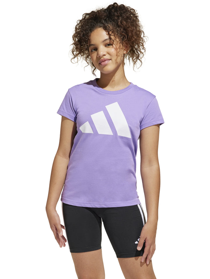 Niña vistiendo una camiseta deportiva Adidas de color morado con logo blanco y shorts negros.