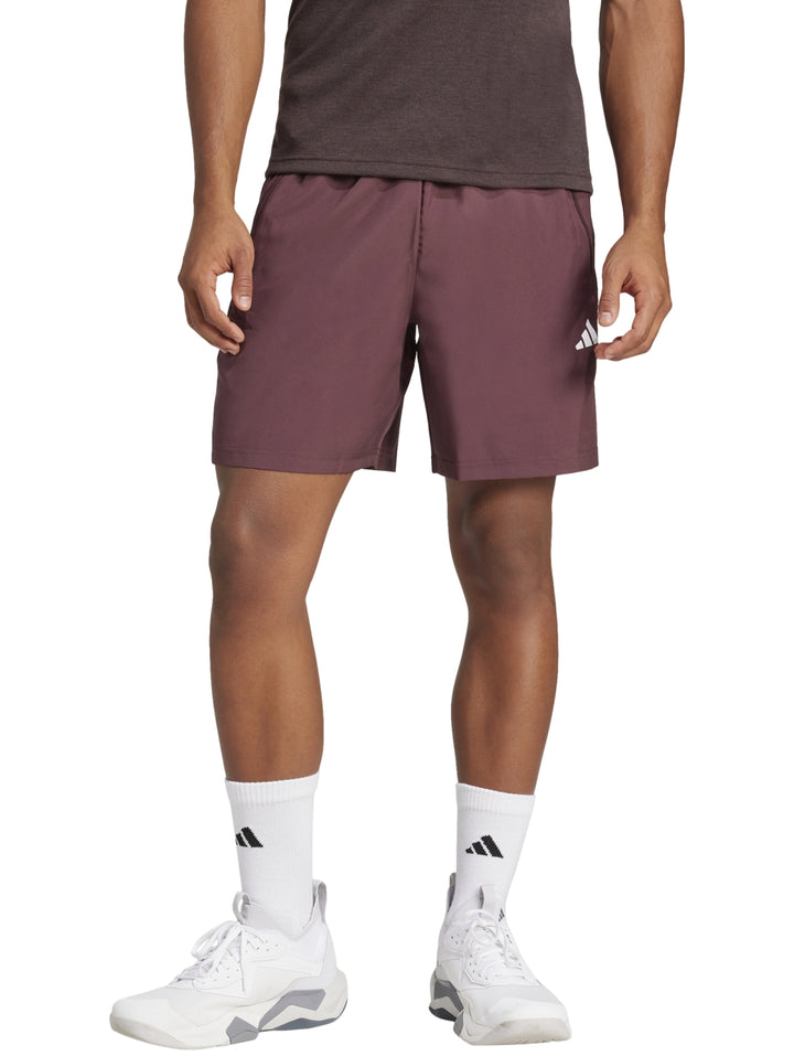 Hombre vistiendo shorts deportivos Adidas color borgoña con calcetines y tenis blancos.