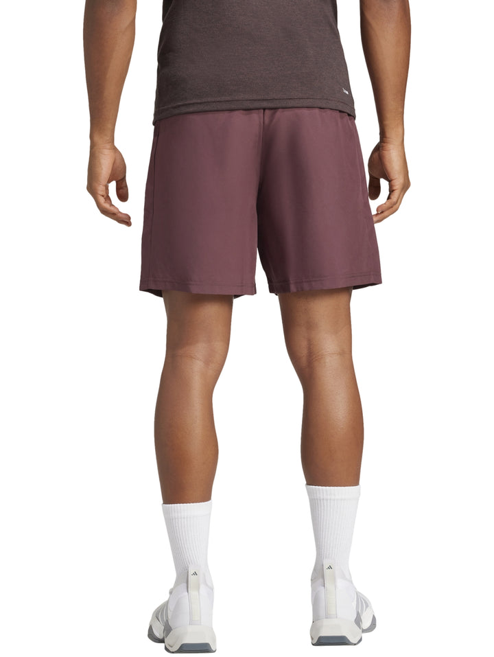 Hombre vistiendo shorts deportivos Adidas color borgoña con calcetines y tenis blancos.